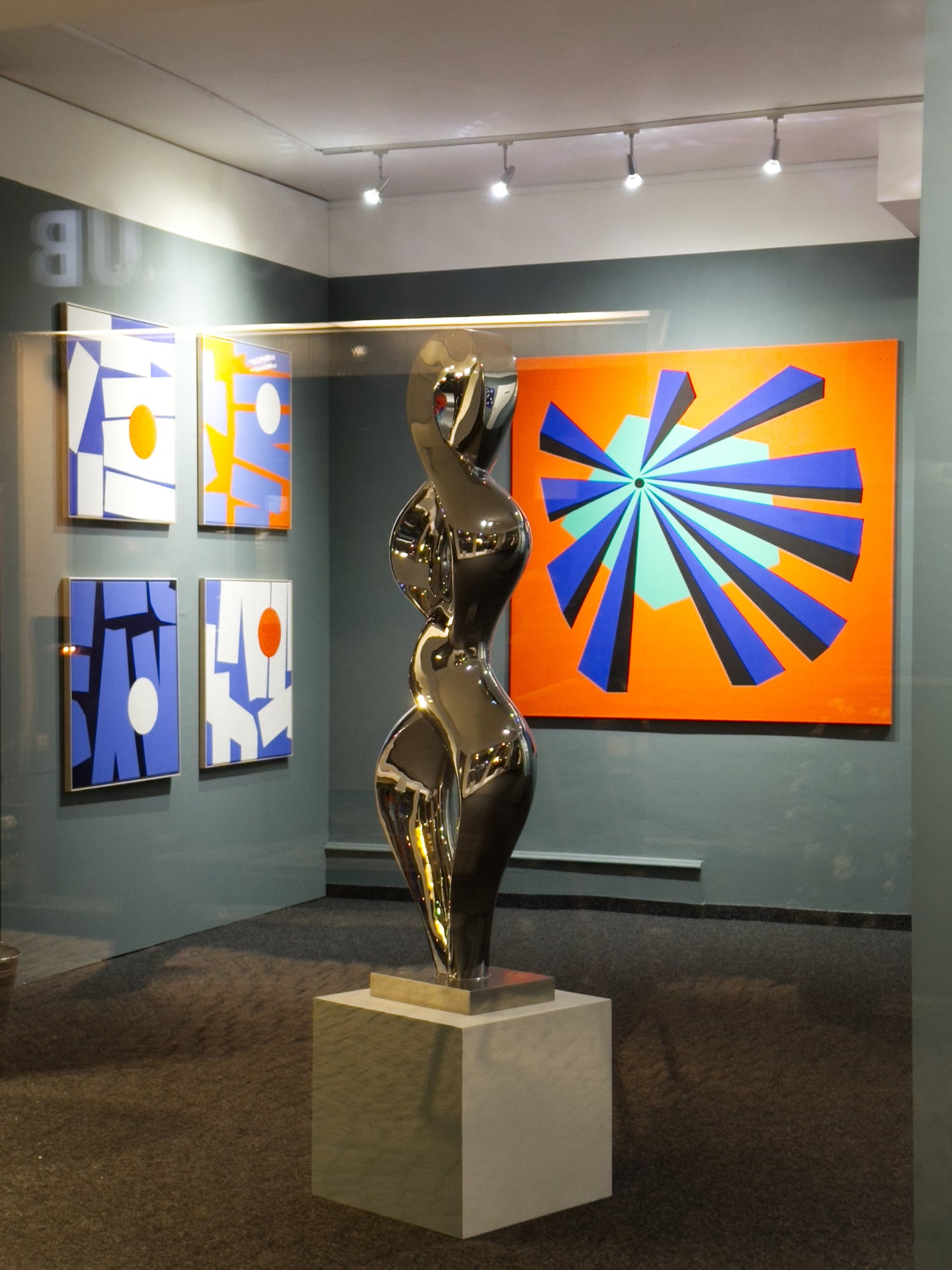 Nighttime installation view at Andermatt Art Gallery (AGA): Eilena Braye exhibition with a sculpture by Evelyne Brader-Franck, science-inspired abstract works in the background.
