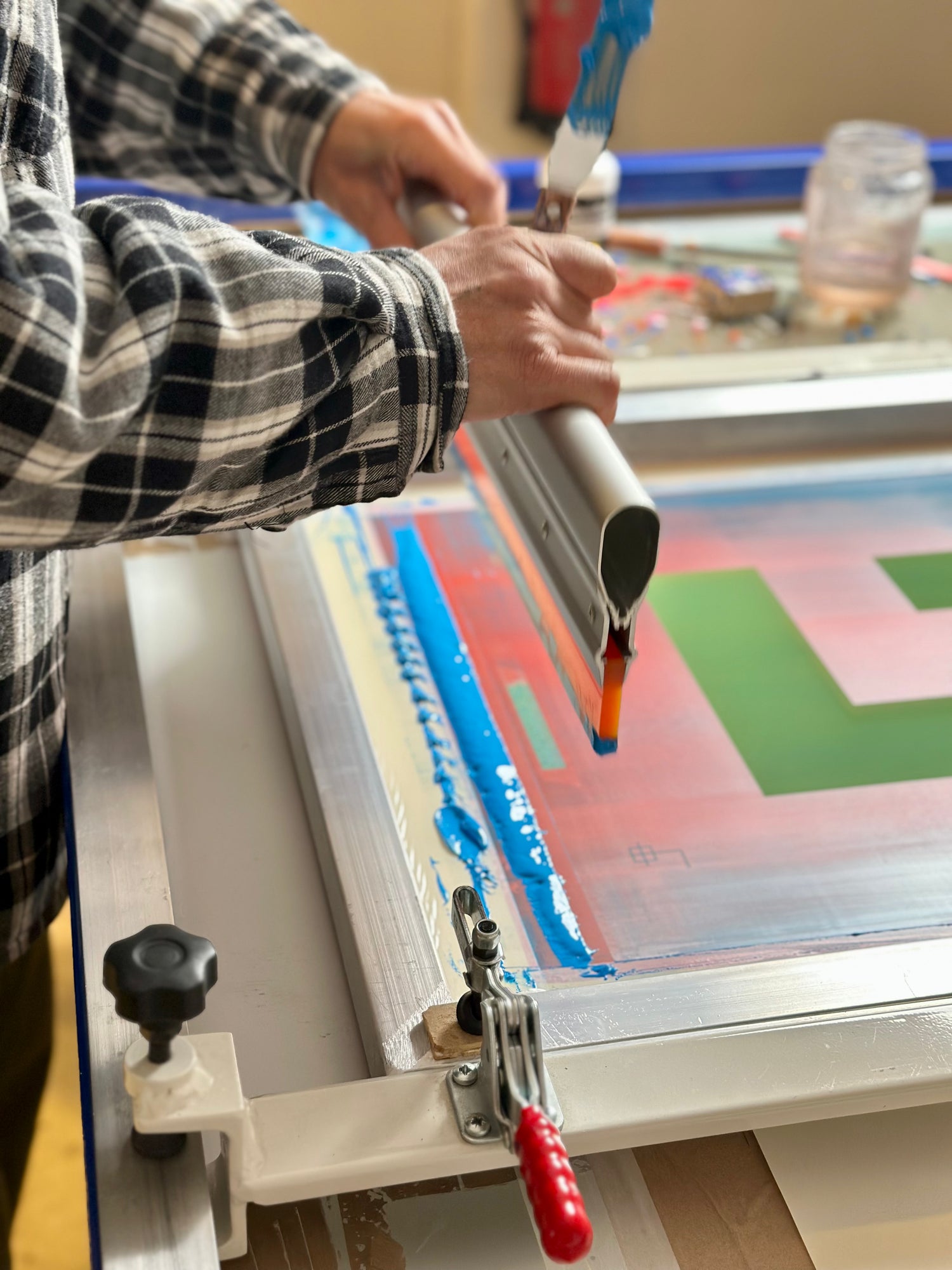 Artisan using a squeegee to print layers of color on fine art paper at Murotopia Studio.